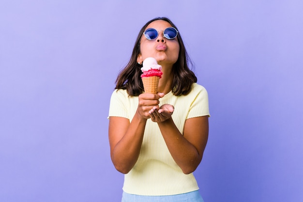 Jonge gemengde rasvrouw die een roomijs eet die lippen vouwt en palmen houdt om luchtkus te verzenden.