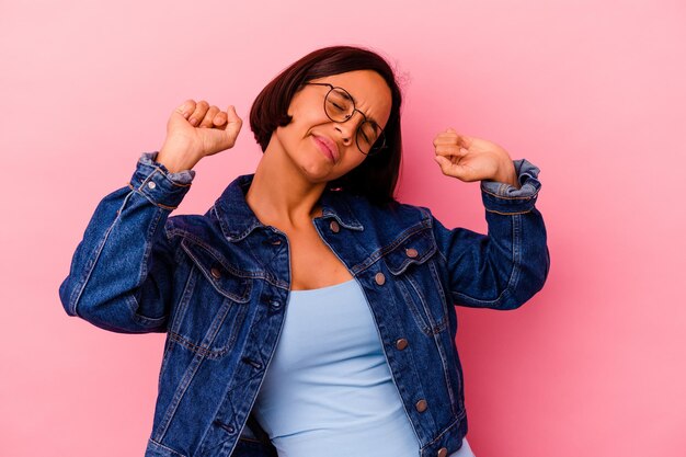 Jonge gemengde rasvrouw die op roze armen, ontspannen positie uitrekt.