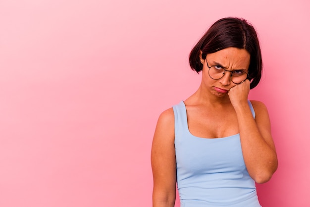 Jonge gemengde rasvrouw die op roze muur wordt geïsoleerd die verdrietig en peinzend voelt, exemplaarruimte bekijkt.