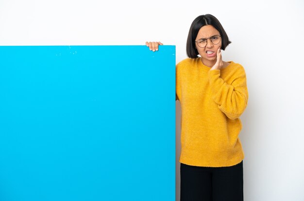 Jonge gemengde rasvrouw met een groot blauw aanplakbiljet dat op witte achtergrond met kiespijn wordt geïsoleerd