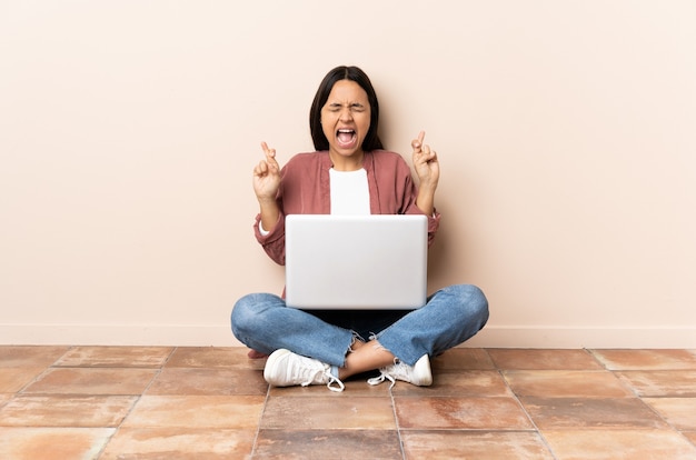 Jonge gemengde rasvrouw met laptopzitting op de vloer