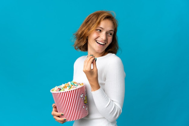 Jonge georgische geïsoleerde vrouw die een grote emmer popcorns houdt