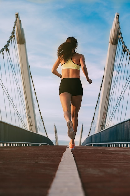 Jonge geschikte blondevrouw die op de brug lopen