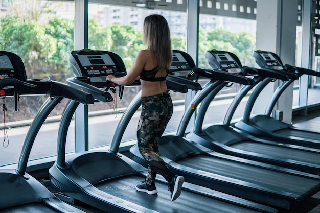 Jonge geschikte vrouw die lopende oefening in gymnastiek doet bij loopband speedwalk lopende weg.