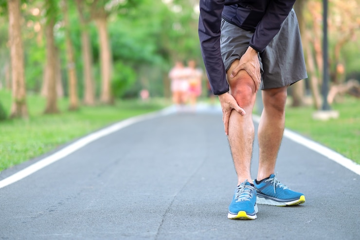 Foto jonge geschiktheidsmens die zijn verwonding van het sportenbeen houden.