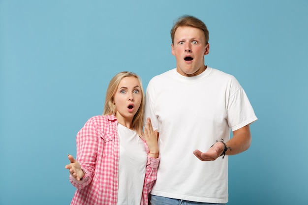 Jonge geschokte paar vrienden man en vrouw in wit roze lege t-shirts poseren