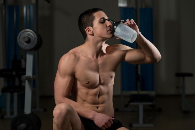 Jonge gespierde man die een waterfles drinkt