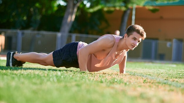 Jonge gespierde man doet push ups op stadion