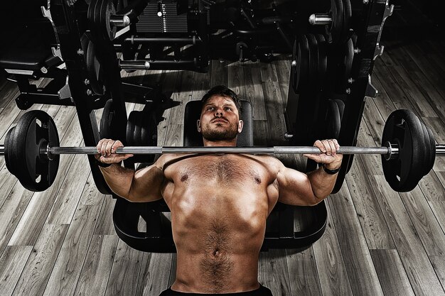 Jonge gespierde man tillen een barbell bench press in de sportschool. mooi lichaam, doel behalen, sport als een manier van leven.