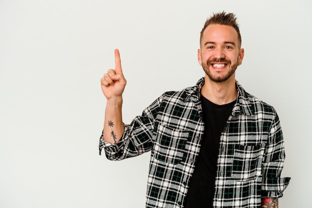 Jonge getatoeëerde blanke man geïsoleerd op een witte muur met nummer één met vinger.