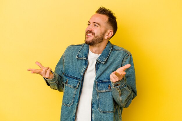 Jonge getatoeëerde blanke man geïsoleerd op gele achtergrond vrolijk lachen veel. Geluk concept.