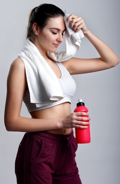 Jonge gezonde fitness vrouw met handdoek en water