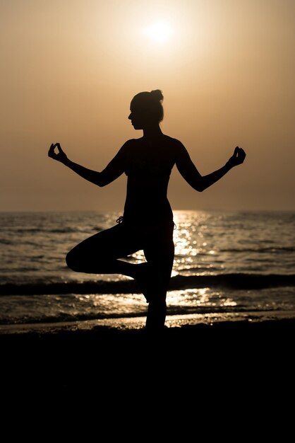 Jonge gezonde vrouw beoefenen van Yoga Fitness Oefening op het strand bij zonsondergang Gezonde levensstijl Concept kopie ruimte tekst