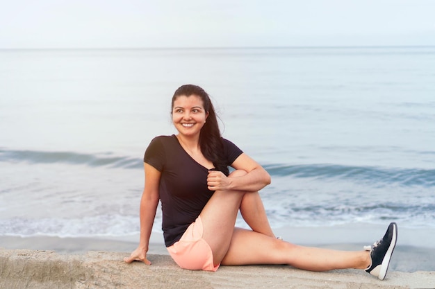 Jonge gezonde vrouw die yoga beoefent op het strand