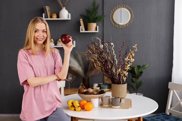 Jonge gezonde vrouw met een appel dichtbij de eettafel