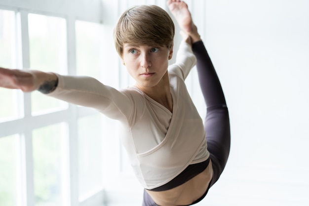 Jonge glimlachende aantrekkelijke vrouw die yoga beoefent