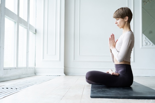 Jonge glimlachende aantrekkelijke vrouw die yoga beoefent