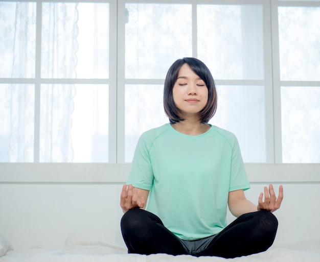 Jonge glimlachende aantrekkelijke yogi-vrouw die yoga beoefent