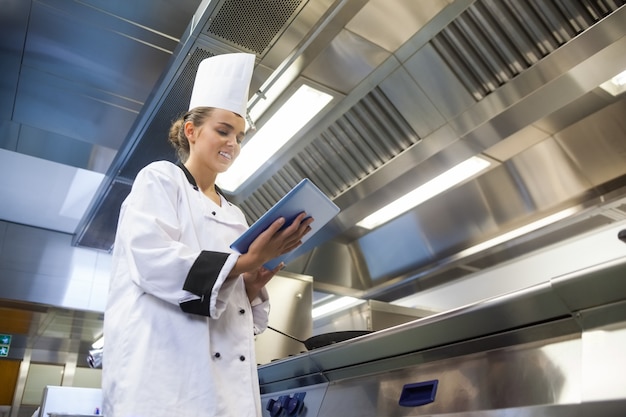 Jonge glimlachende chef-kok die tablet gebruikt