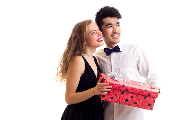 Jonge glimlachende man met zwart haar en jonge mooie vrouw met lang blond haar met rood cadeau