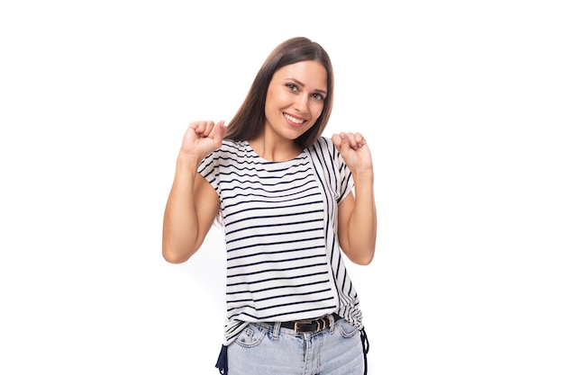 Jonge glimlachende mooie Europese brunette vrouw gekleed in een gestreepte T-shirt op een witte achtergrond met