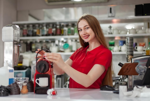 Jonge glimlachende vrouw barista die koffie maakt in een koffiemachine