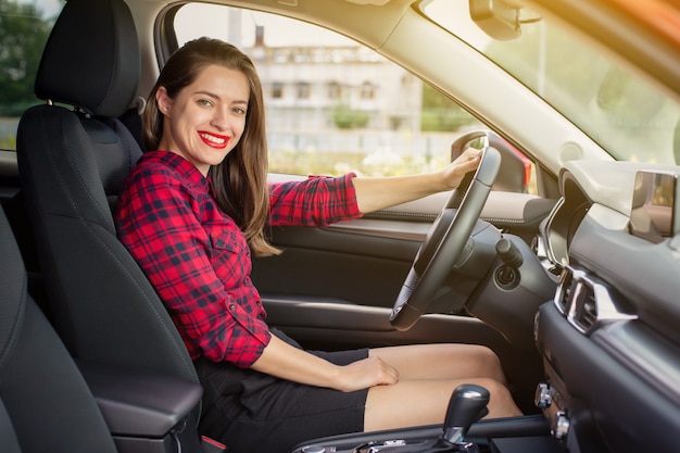 Jonge glimlachende vrouw die een moderne auto drijft