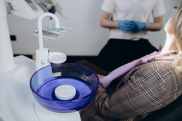 Jonge glimlachende vrouw die haar tanden laat controleren door tandarts tijdens afspraak bij tandheelkundige kliniek