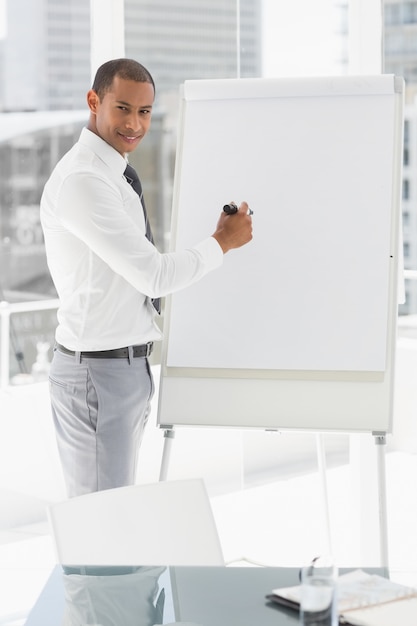 Jonge glimlachende zakenman die bij whiteboard met teller voorstellen
