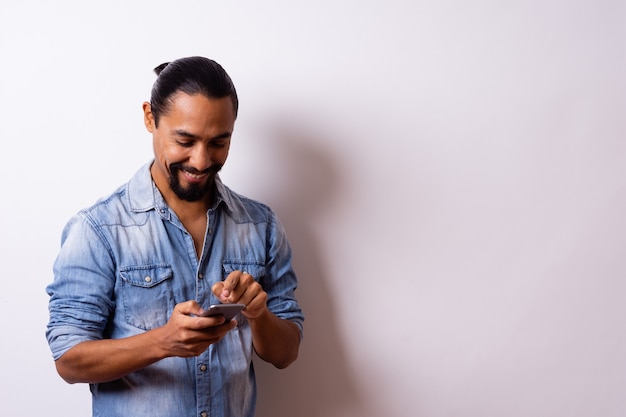 Jonge, goed verzorgde moderne Latino met baard glimlacht tevreden en wijst met zijn vinger naar zijn tablet. Bedrijfsconcept.