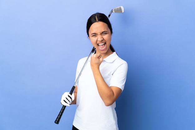 Jonge golfspelervrouw die over geïsoleerde kleurrijke achtergrond een overwinning viert