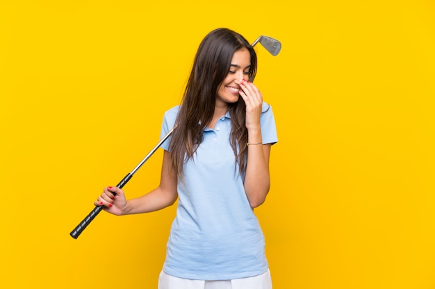 Jonge golfspelervrouw over geïsoleerde gele muur die veel glimlacht