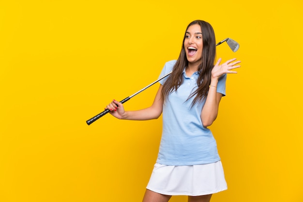 Jonge golfspelervrouw over geïsoleerde gele muur met verrassingsgelaatsuitdrukking