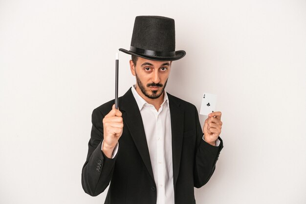Jonge goochelaar man met toverstaf en magische kaart geïsoleerd op een witte achtergrond