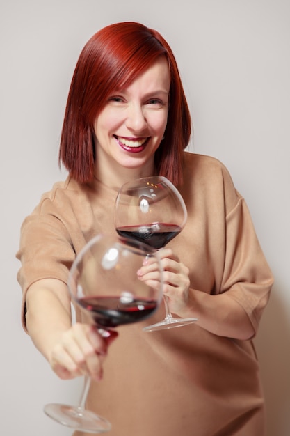 Jonge grappige redhaired vrouwensommelier met wijnglazen