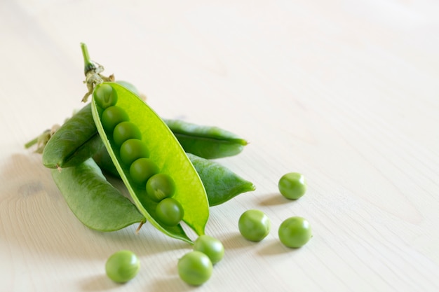 Jonge groene erwten op witte houten tafel.