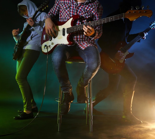 Foto jonge groep elektrische gitaar spelen op verlichte mistige achtergrond