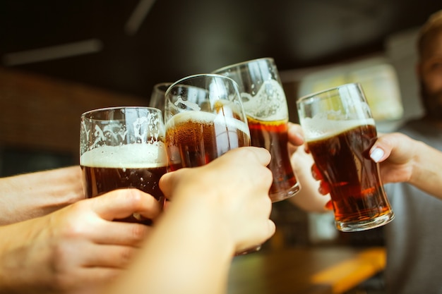 Foto jonge groep vrienden die bier drinken met plezier lachen en samen vieren close-up rammelende