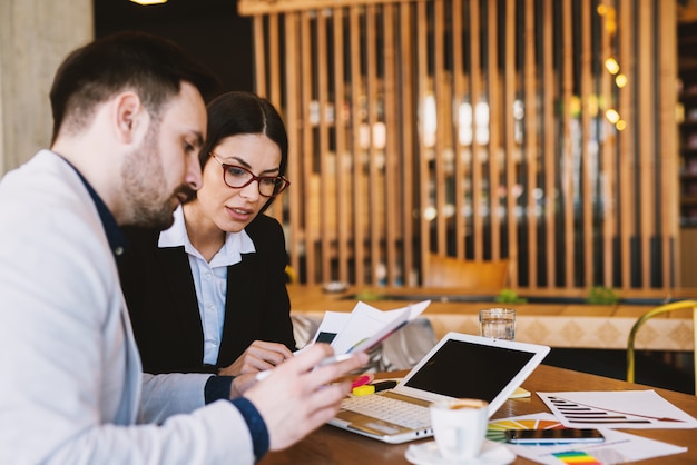 Jonge hardwerkende business hogescholen zitten in een coffeeshop na het werk en het schrijven van rapporten.