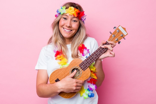 Jonge Hawaiiaanse vrouw die een ukelele speelt die op roze achtergrond wordt geïsoleerd