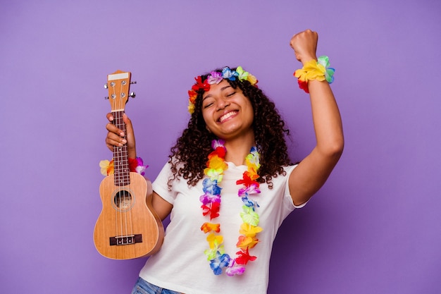 Jonge hawaiiaanse vrouw die ukelele speelt geïsoleerd op paars