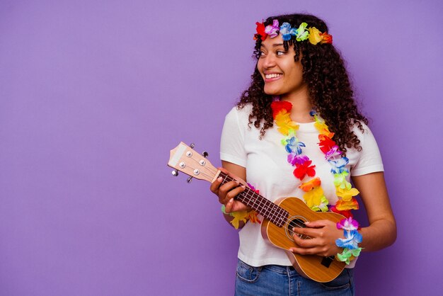 Jonge Hawaiiaanse vrouw die ukelele speelt geïsoleerd op paarse achtergrond