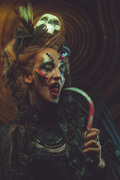 Jonge heks die sikkel houdt Heldere make-up schedel rook Halloween thema Studio opname