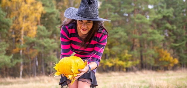 Jonge heks met pompoen in het herfst bos halloween concept