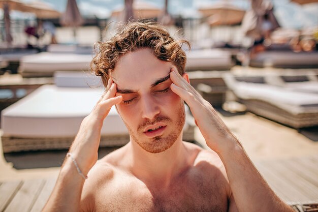 Jonge hete man met hoofdpijn bij het zwembad