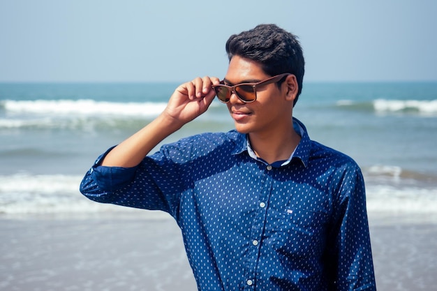 Jonge hindoe stijlvolle man poseren met zonnebril actieve strandvakantie op semmertime gelukkig Goa India strand zonnebrandcrème spf bescherming concept