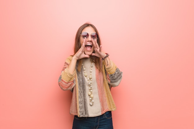 Jonge hippievrouw die op roze achtergrond iets gelukkig aan de voorzijde schreeuwen