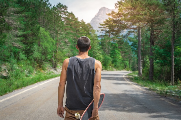 Jonge hipster met een cool longboard in zijn hand