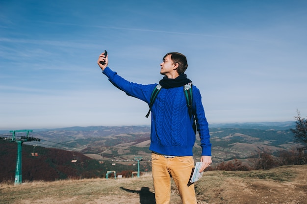 Jonge hipster neemt foto door smartphone op de top van de berg