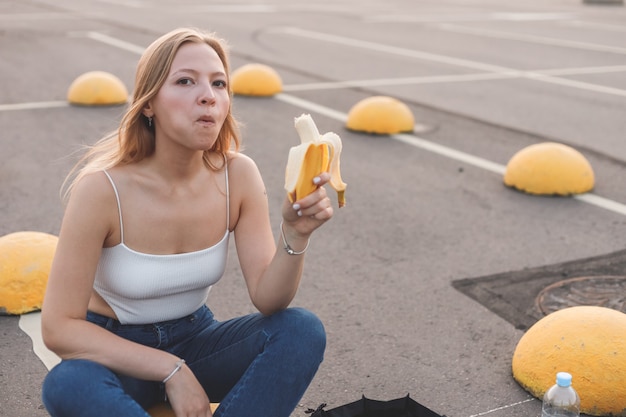 Jonge hipster sportieve vrouw die een pauze neemt van skaten die banaan eet